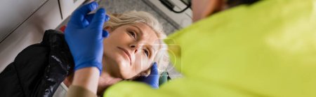 Photo for High angle view of mature woman looking at blurred paramedic in emergency vehicle, banner - Royalty Free Image