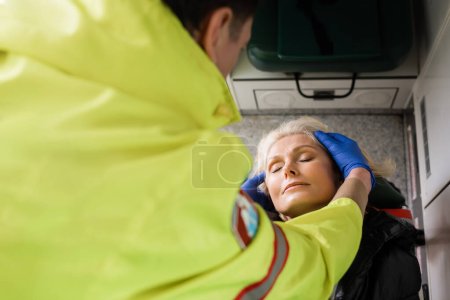 Photo for High angle view of blurred paramedic checking mature patient in emergency vehicle - Royalty Free Image