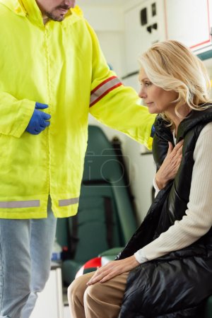 Photo for Paramedic in uniform calming mature woman in emergency vehicle - Royalty Free Image