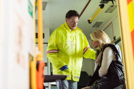 Paramédico en uniforme calmante mujer de mediana edad en coche de emergencia 