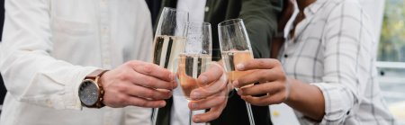 Cropped view of multiethnic business people clinking champagne in office, banner 