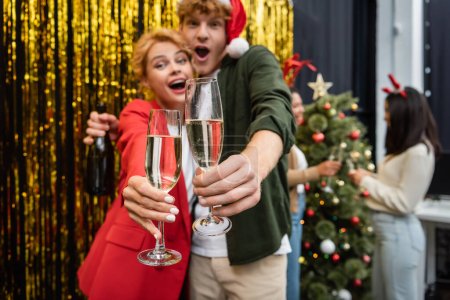 Photo for Blurred business people holding glasses of champagne during Christmas corporate party in office - Royalty Free Image