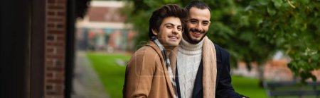 Photo for Young and fashionable gay couple in coats in scarfs smiling at camera outdoors, banner - Royalty Free Image