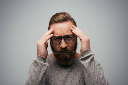 Photo for Stressed man in eyeglasses looking at camera while touching forehead isolated on grey - Royalty Free Image