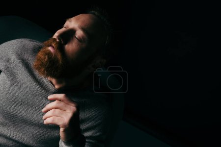 Stylish bearded model posing isolated on black with lighting and shadow 