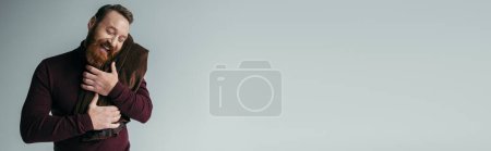 Téléchargez les photos : Homme barbu au col roulé embrassant blazer et souriant isolé sur gris, bannière - en image libre de droit