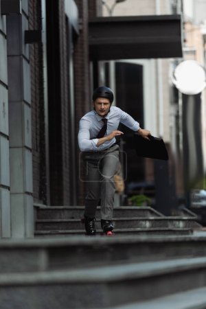 Young businessman on roller skates skating on stairs on urban street 