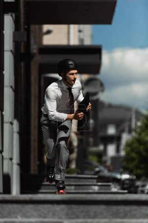 Young businessman in formal wear and roller skates riding on urban street 