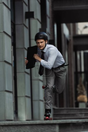 Young businessman on roller skates holding briefcase while riding on urban street 