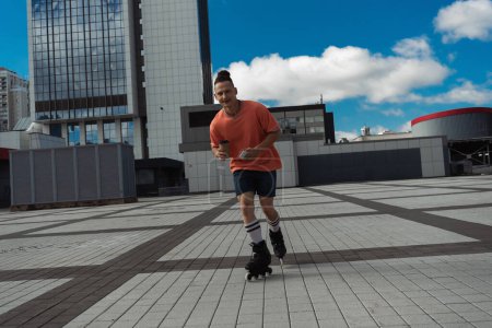 Hombre alegre en patines con teléfono inteligente y café para ir en la calle de la ciudad 