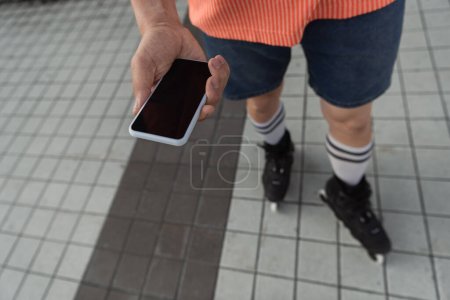 Photo for Cropped view of roller skater holding smartphone with blank screen outdoors - Royalty Free Image