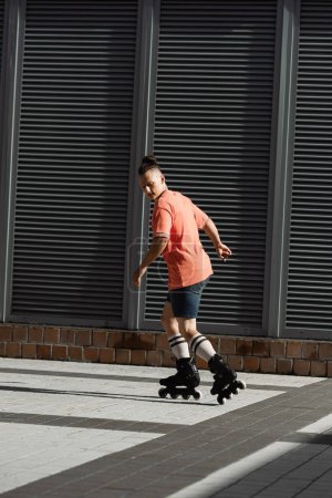 Young man roller skating on urban street at daytime 