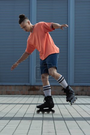 Young man in casual clothes riding roller blades outdoors 