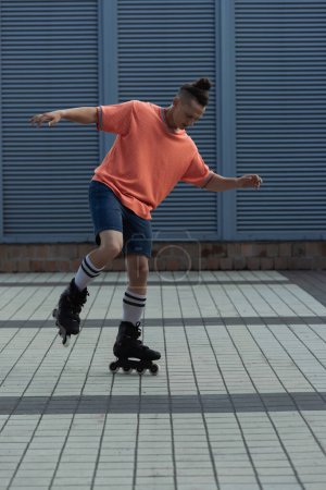 Young man in roller blades and shorts riding outdoors 