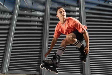 Foto de Hombre concentrado en calcetines y rodillos de rodilla saltando cerca del edificio en la calle urbana durante el día - Imagen libre de derechos