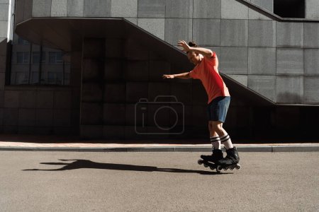 Téléchargez les photos : Vue latérale de l'homme dans les patins à roues alignées sur la rue urbaine le jour - en image libre de droit