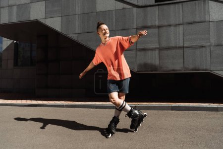 Fröhlicher junger Mann mit Rollerblades steht auf Asphalt auf Straße 