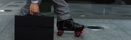 cropped view of businessman in roller skate holding briefcase on street, banner