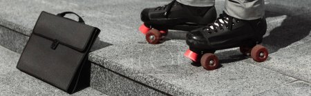 vue partielle de l'homme d'affaires en patins à roulettes près de la mallette noire sur la rue urbaine, bannière
