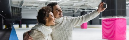 Photo for Positive interracial couple taking selfie on smartphone on ice rink, banner - Royalty Free Image