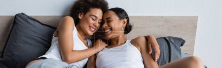 Téléchargez les photos : Heureux et lesbienne couple afro-américain avec les yeux fermés couché sur le lit, bannière - en image libre de droit