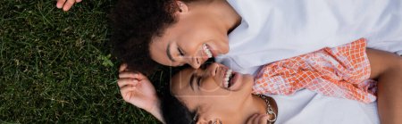 vue du haut des femmes lesbiennes afro-américaines heureuses allongées sur l'herbe, bannière
