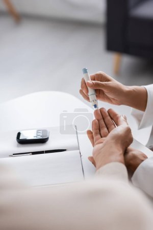 cropped view of african american doctor taking blood sample of patient with diabetes in clinic 