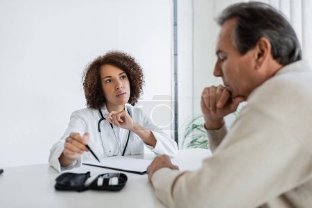 Photo for African american doctor pointing at diabetes kit near mature patient in hospital - Royalty Free Image