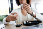 Cropped view of blurred african american woman holding test strip of glucometer in office  puzzle #629001134