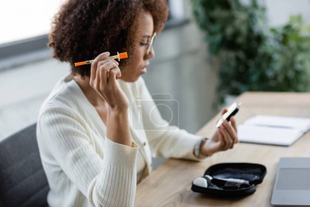 Téléchargez les photos : Femme d'affaires afro-américaine floue avec diabète tenant la seringue et le glucomètre au bureau - en image libre de droit
