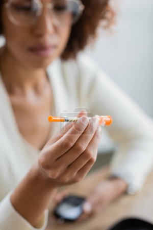 Téléchargez les photos : Femme d'affaires afro-américaine floue diabétique tenant une seringue d'insuline au bureau - en image libre de droit