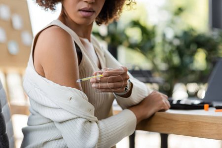 Téléchargez les photos : Vue recadrée d'une femme d'affaires afro-américaine faisant une injection d'insuline au bureau - en image libre de droit