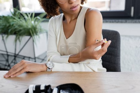 Ausgeschnittene Ansicht einer afrikanisch-amerikanischen Geschäftsfrau bei der Insulinspritze in der Nähe von Diabetes-Kit 