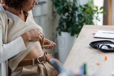 Ausgeschnittene Ansicht einer afrikanisch-amerikanischen Geschäftsfrau bei der Insulinspritze in der Nähe von Diabetes-Kit im Büro 