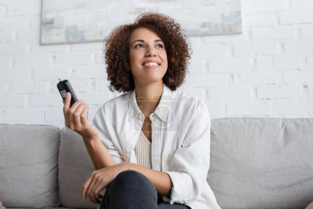 Positive african american woman with diabetes holding glucometer at home 