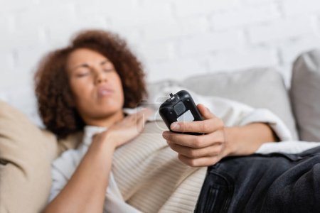 Téléchargez les photos : Femme afro-américaine diabétique se sentant mal et tenant glucomètre à la maison - en image libre de droit
