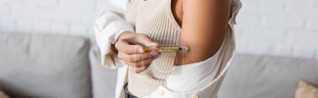 Vista recortada de una mujer afroamericana con diabetes que se inyecta insulina en el brazo, pancarta 