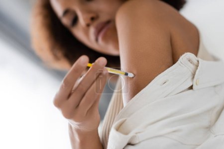 Vista de ángulo bajo de la mujer afroamericana con jeringa inyectable de insulina en casa 