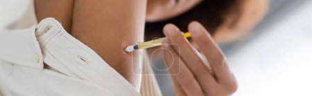 Vista de ángulo bajo de la mujer afroamericana borrosa con diabetes que hace la inyección de insulina, bandera 