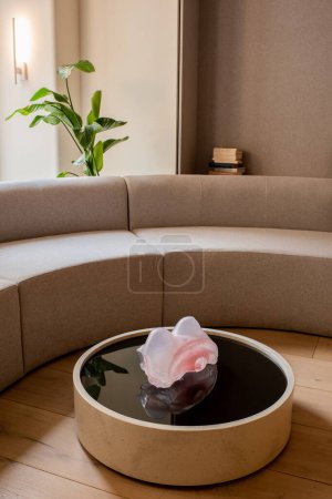 decorative pink figurine on round coffee table near sofa and green plant in hotel 