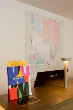 abstract painting on wall near reception desk with art book and computer monitor 