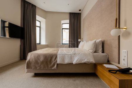 Foto de Flat screen on wall near comfortable bed in modern hotel bedroom - Imagen libre de derechos