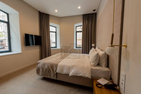 Foto de Telephone near comfortable bed with white bedding in hotel room - Imagen libre de derechos