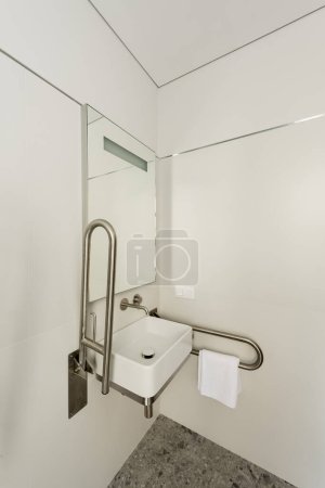 Téléchargez les photos : Interior of white bathroom with sink and mirror for disabled people in hotel - en image libre de droit