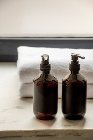 different toiletries near fresh white towels in bathroom of hotel