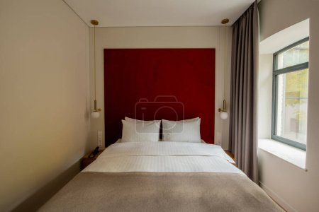 Foto de White pillows on modern bed near to red wall in hotel room - Imagen libre de derechos