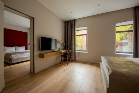 Téléchargez les photos : Flat tv screen near desk and wooden chair next to bedroom in hotel - en image libre de droit