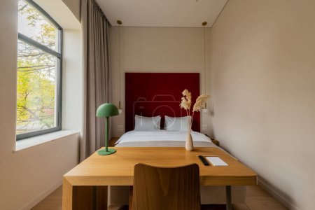 Téléchargez les photos : Wooden desk and chair near comfortable bed in hotel room - en image libre de droit