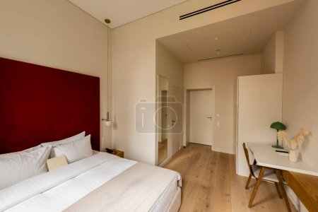 Photo for Wooden chair near workspace and bed in room of hotel - Royalty Free Image