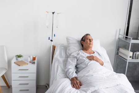 Älterer Mann liegt nahe intravenöser Therapie auf Krankenhausstation
